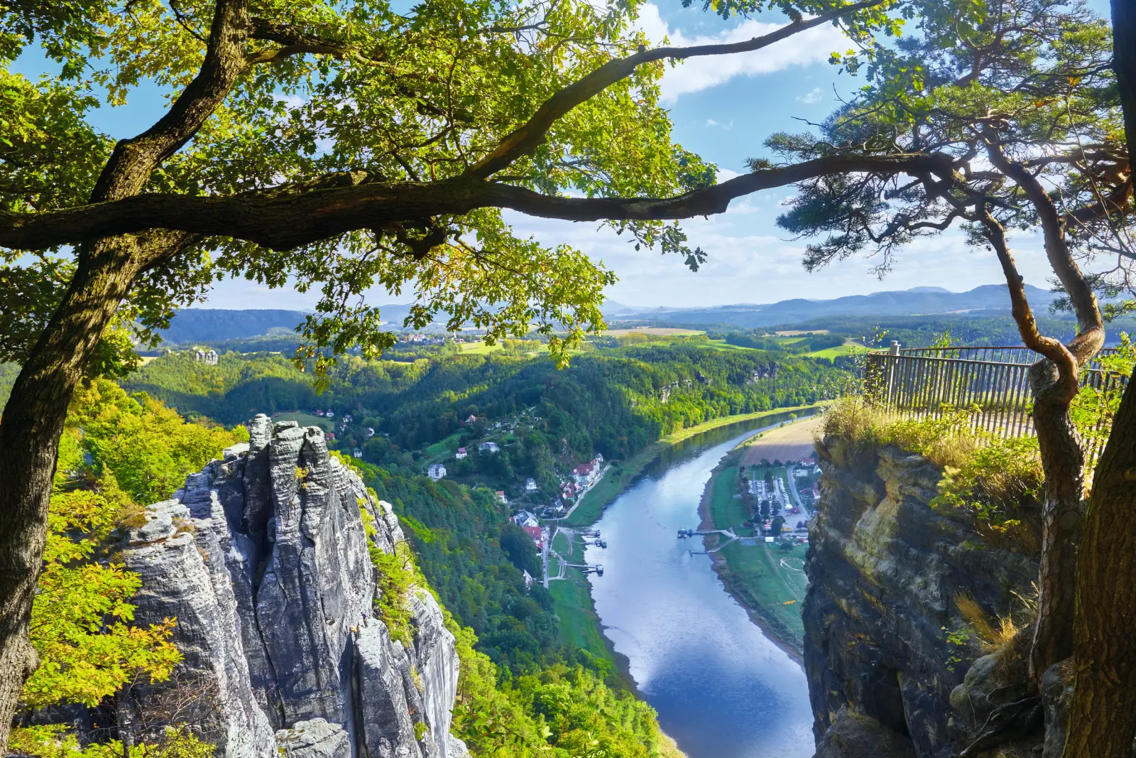 Vue d'une rivière entre rochers et arbres dans un paysage montagneux.
