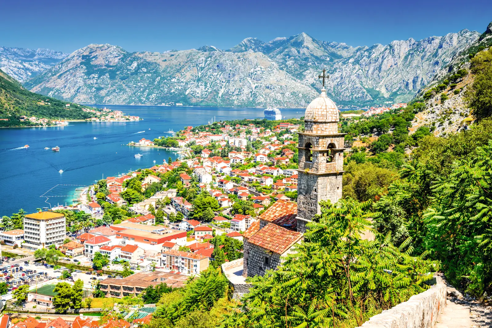 Mittelalterlicher Glockenturm mit Blick auf Küstenstadt Kotor, umgeben von Bergen und Meer.