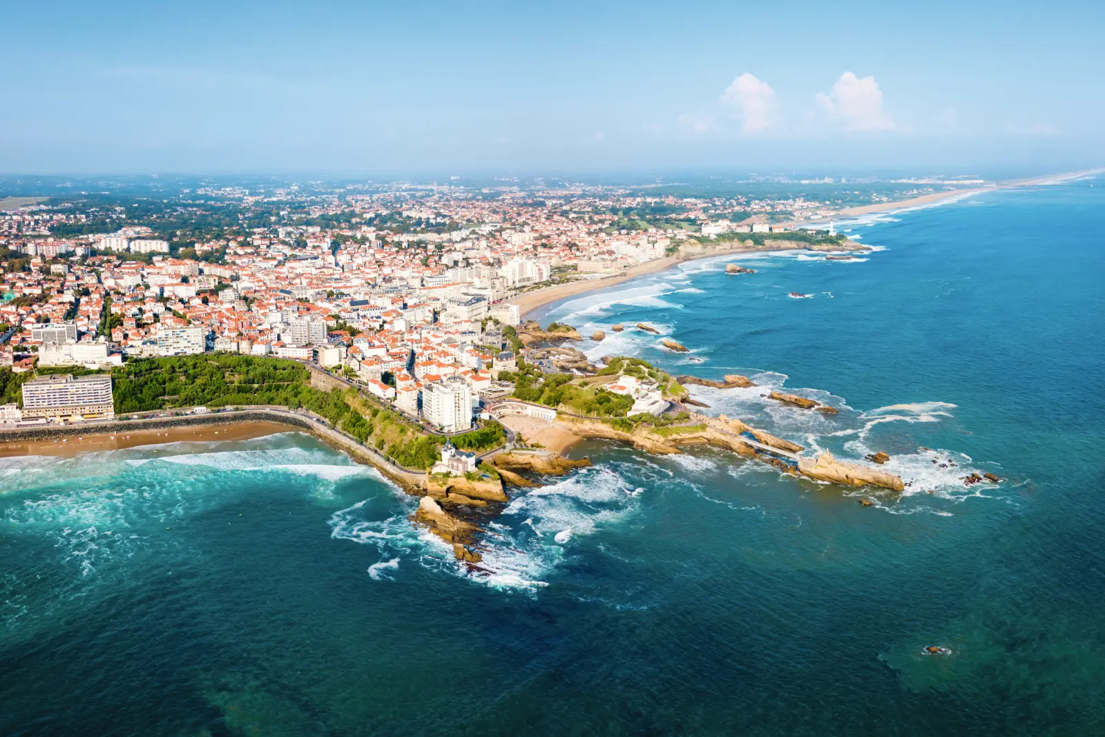 Città costiera con spiagge e mare turchese, vista dall'alto.