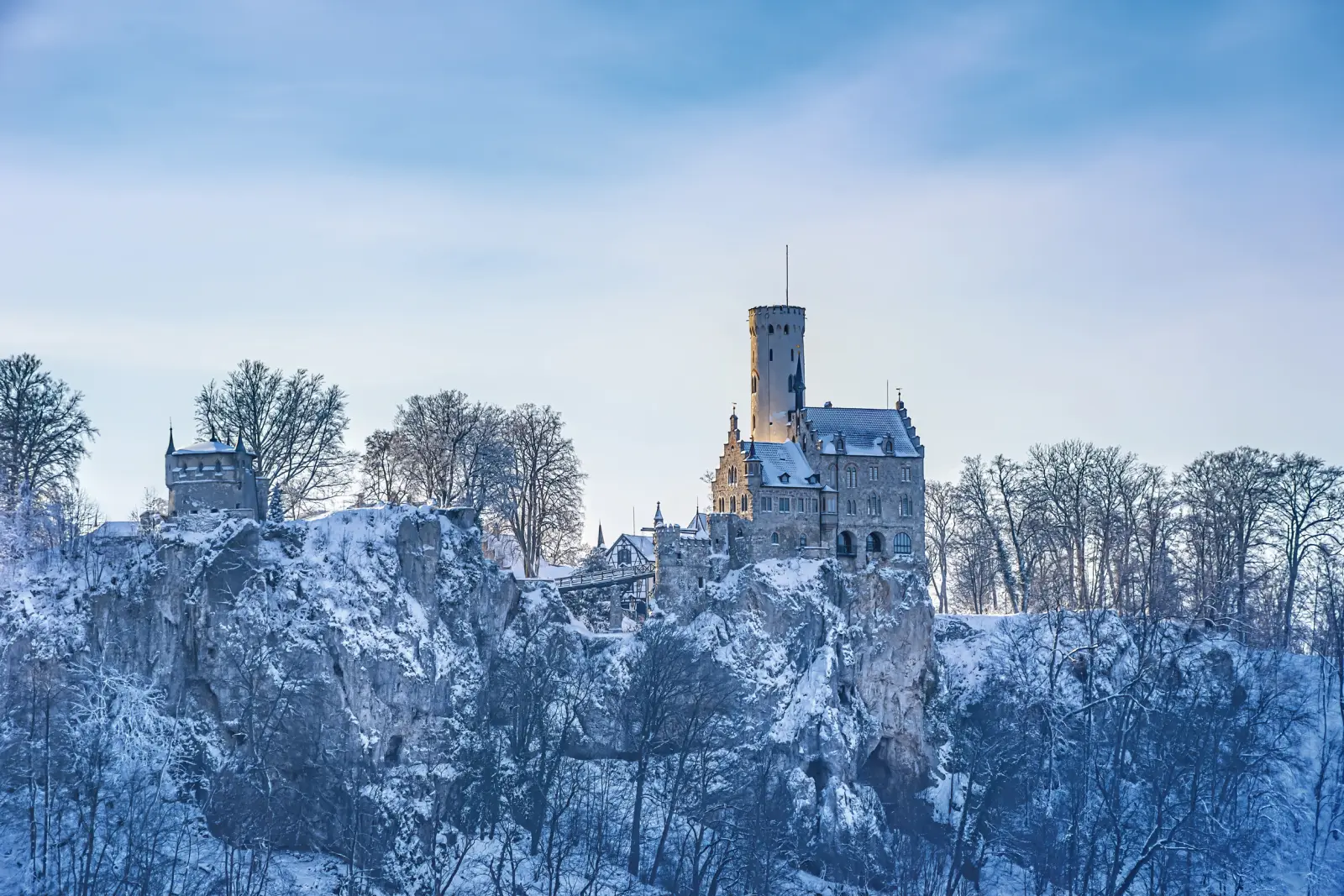 Castle on a snow-covered hill in winter under a blue sky.