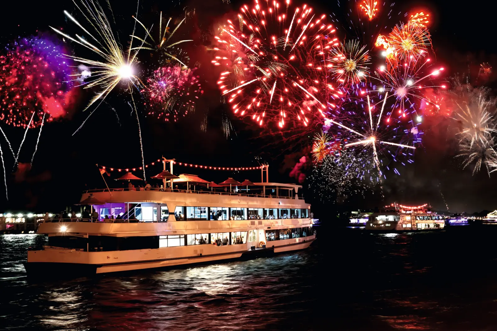 An illuminated ship with fireworks in the night sky.