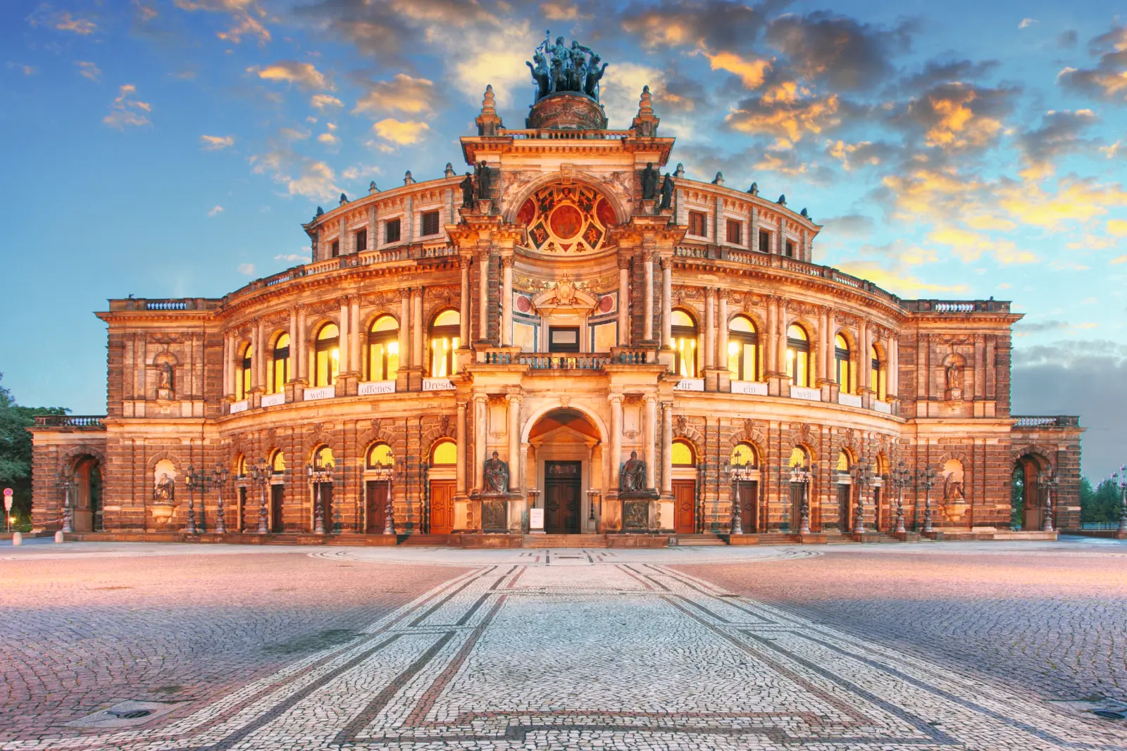 Historic opera house at sunset with an illuminated façade.