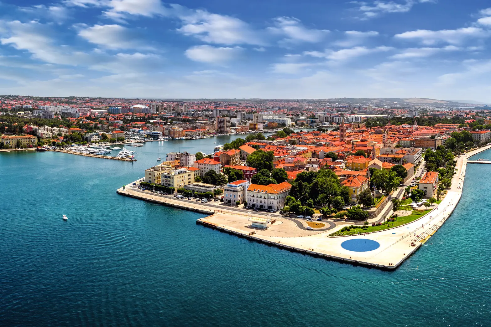 Luftaufnahme einer Küstenstadt mit historischen Gebäuden und blauem Meer.