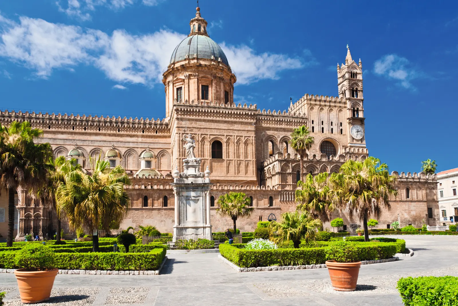 Cattedrale di Palermo con giardini e cielo azzurro sullo sfondo.