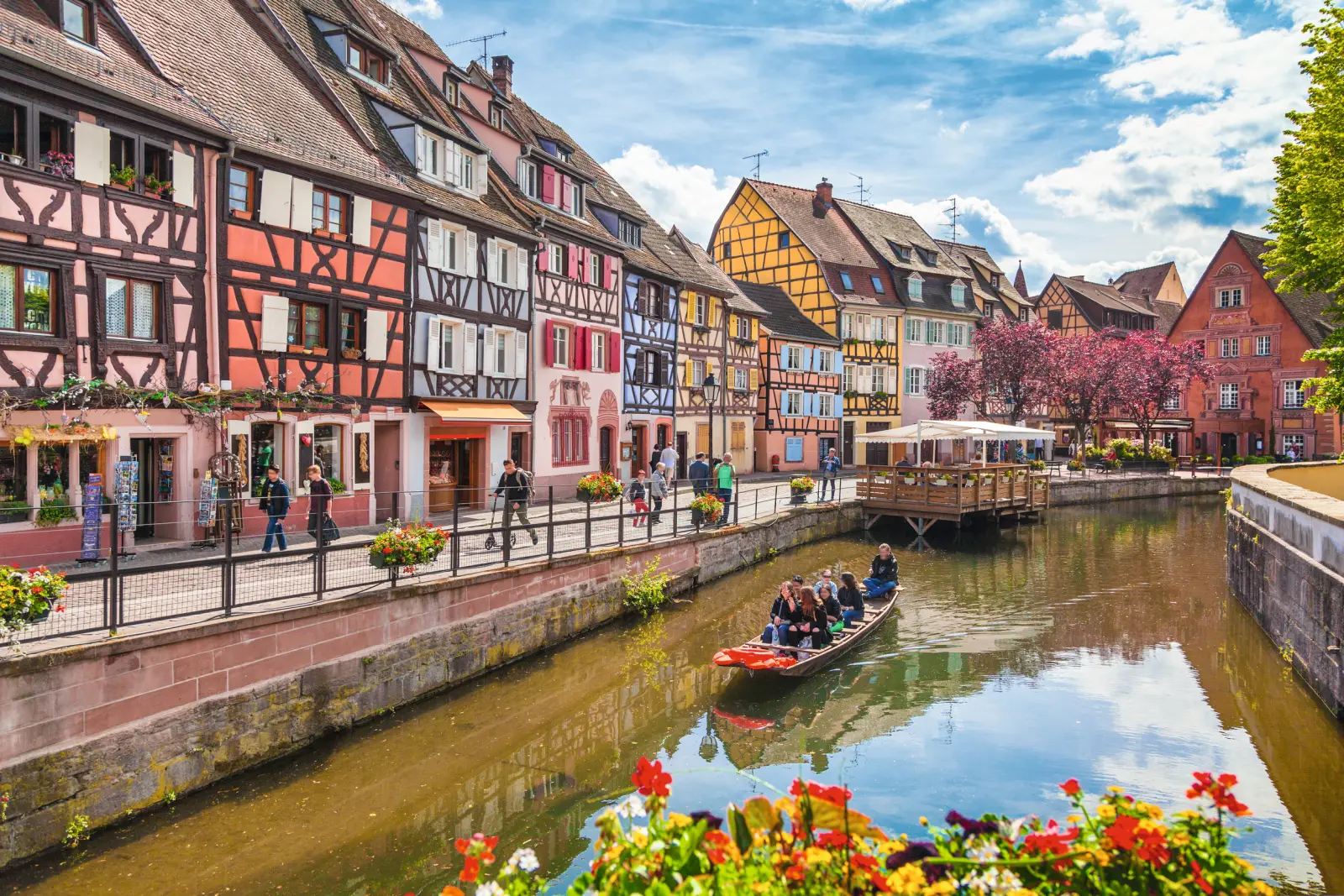 Bunte Fachwerkhäuser und ein Kanal mit Boot in einer europäischen Altstadt.