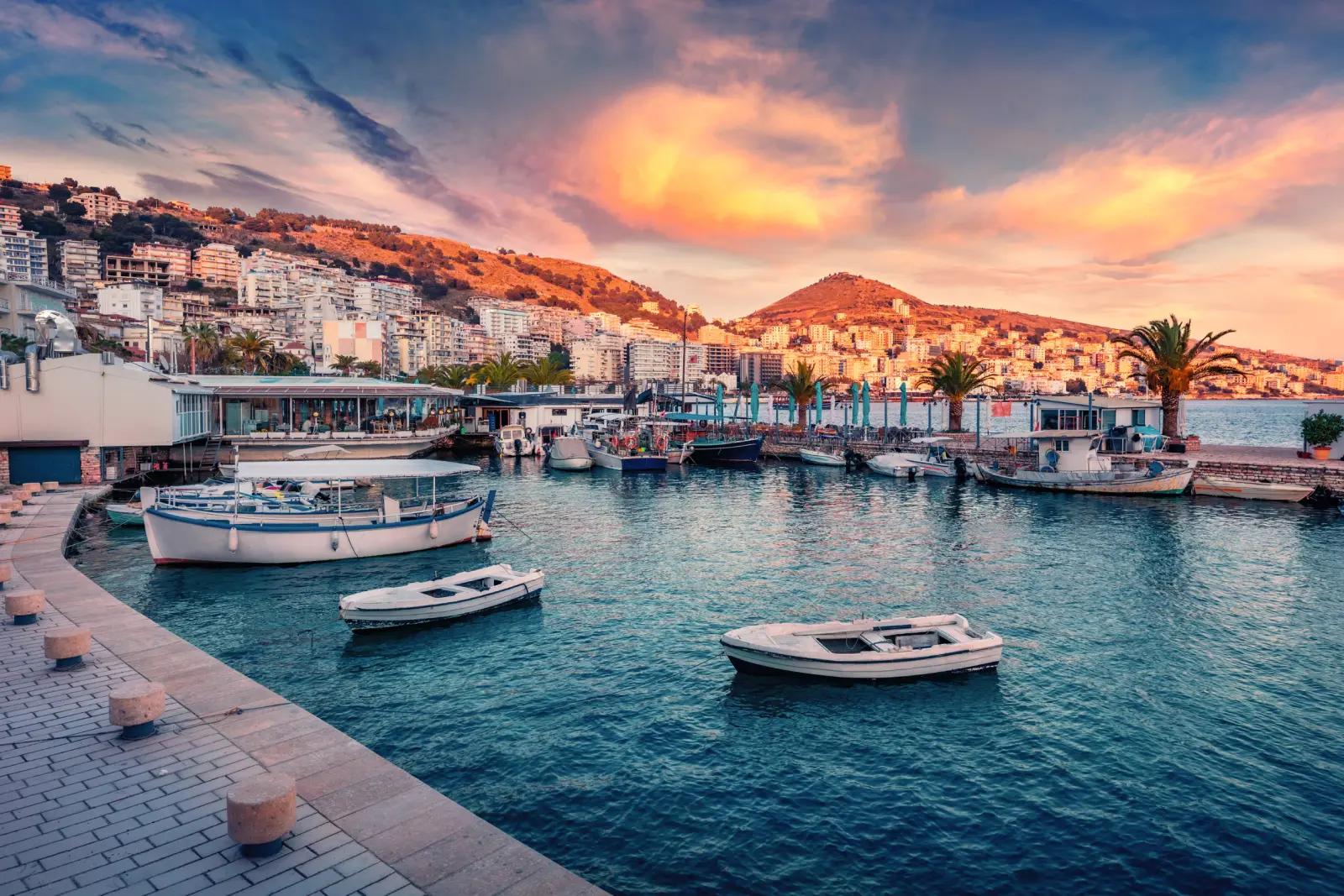 Saranda Marina al tramonto con barche e veduta della città sullo sfondo.