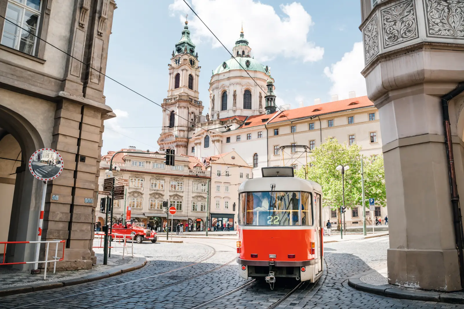 Tram rouge devant une église historique dans une ville européenne.