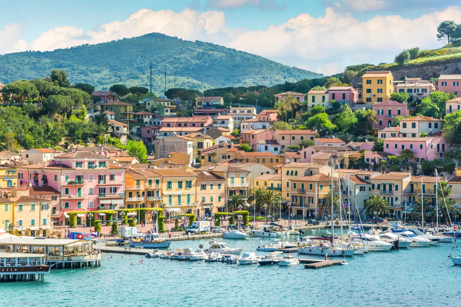 Case colorate e barche al porto davanti a un paesaggio collinare