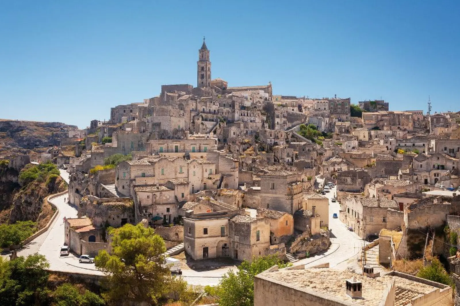 Historic Italian town with old buildings on a hill under a blue sky.