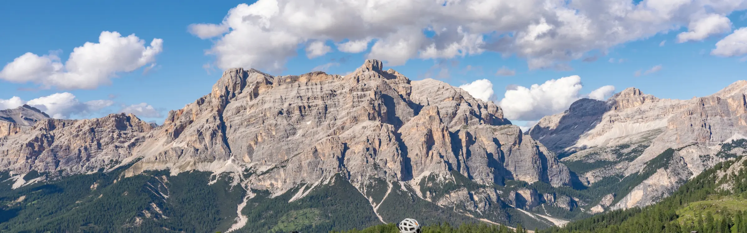 Persona con bicicletta che si gode la vista delle montagne seduta su una panchina.