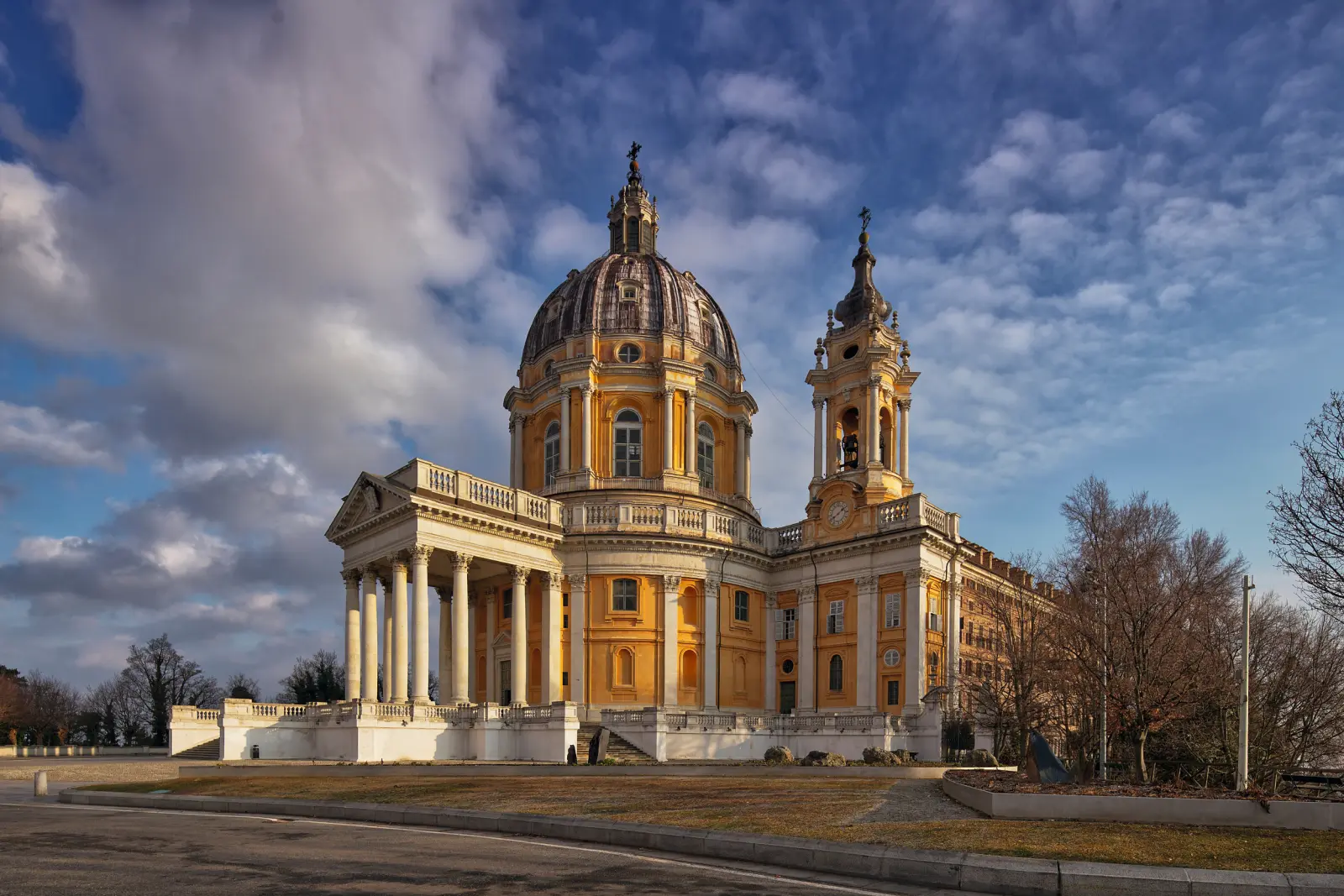 Baroque church with a dome and towers against a cloudy sky.