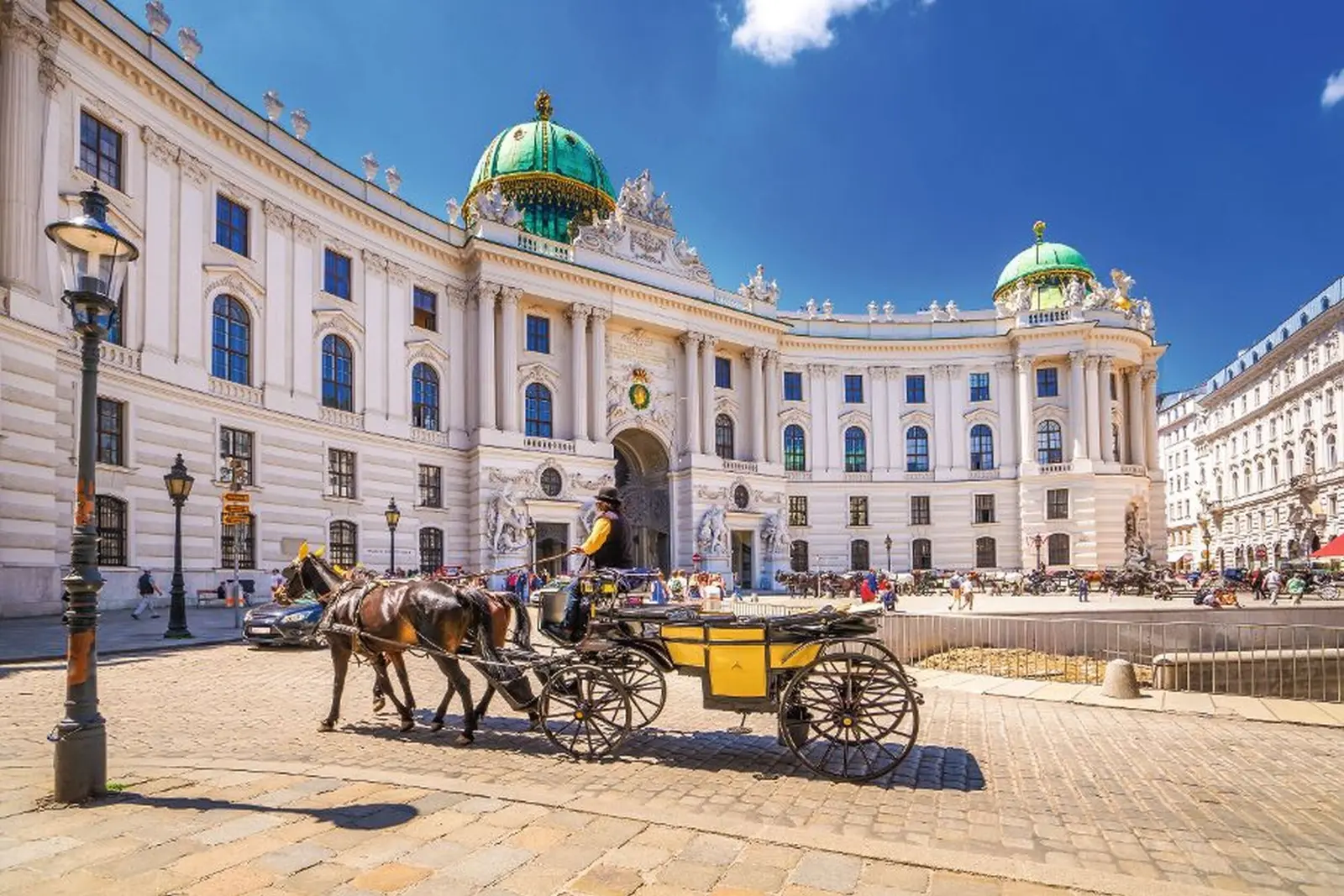 Horse-drawn carriage in front of the Hofburg in Vienna on a sunny day.