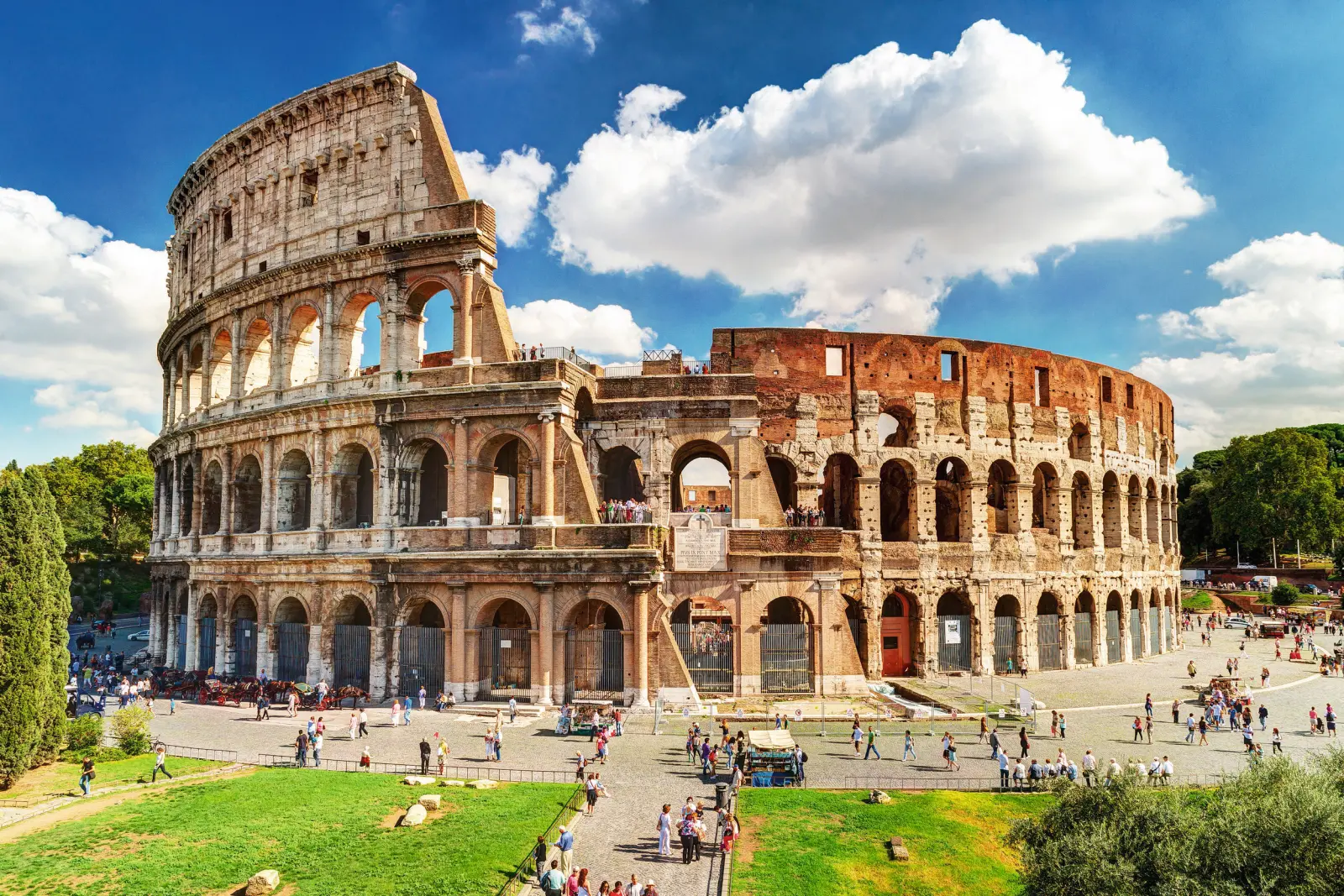 Colosseo a Roma in una giornata di sole, con turisti e cielo azzurro.
