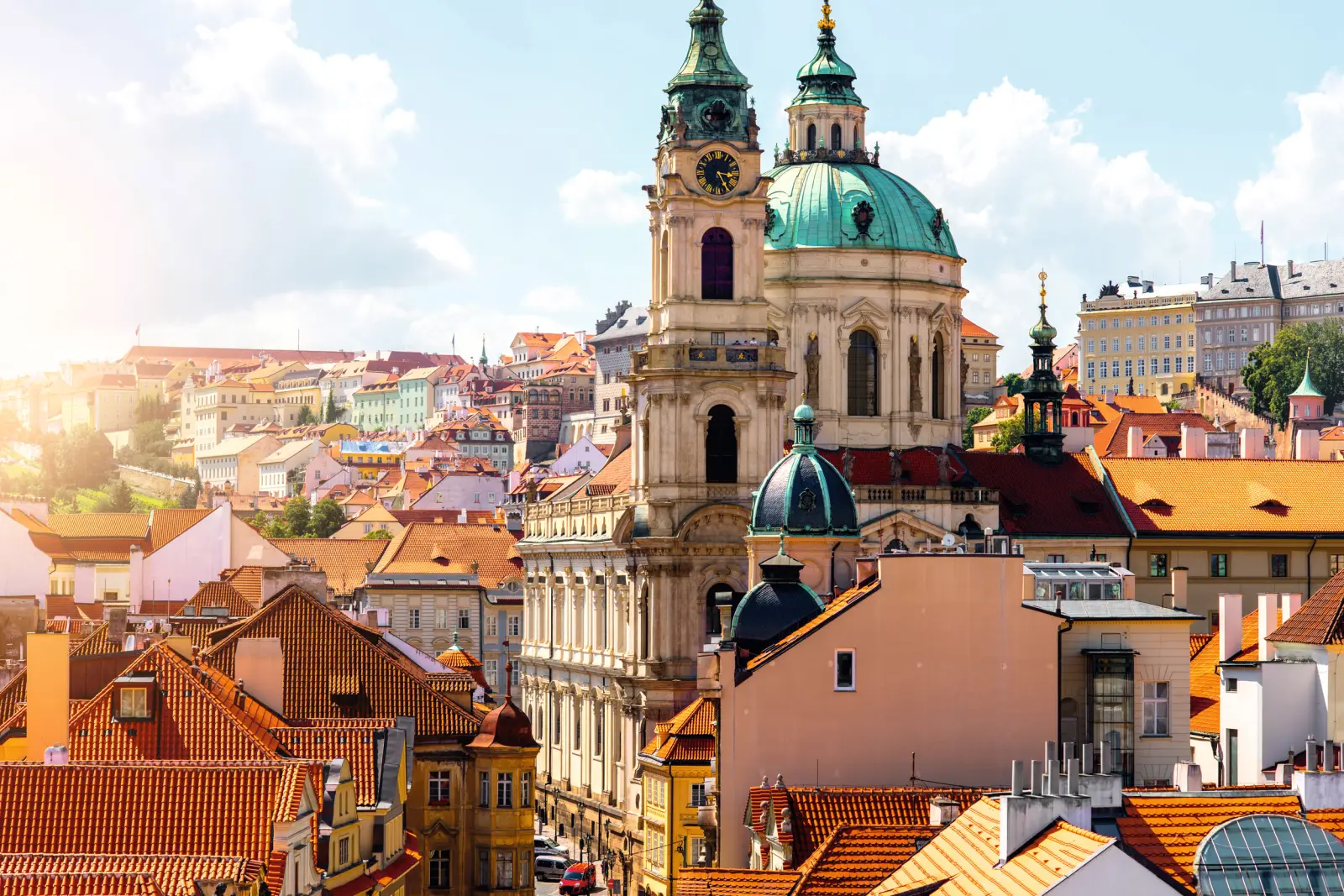View of Prague with St Nicholas Church and colourful buildings in sunny weather.