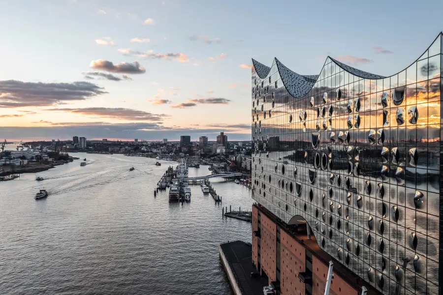 Vista dell'Elbphilharmonie di Amburgo al tramonto, con il porto e l'Elba sullo sfondo.