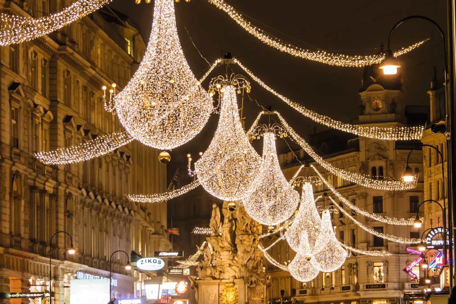 Luci natalizie illuminano una via con edifici storici di notte.