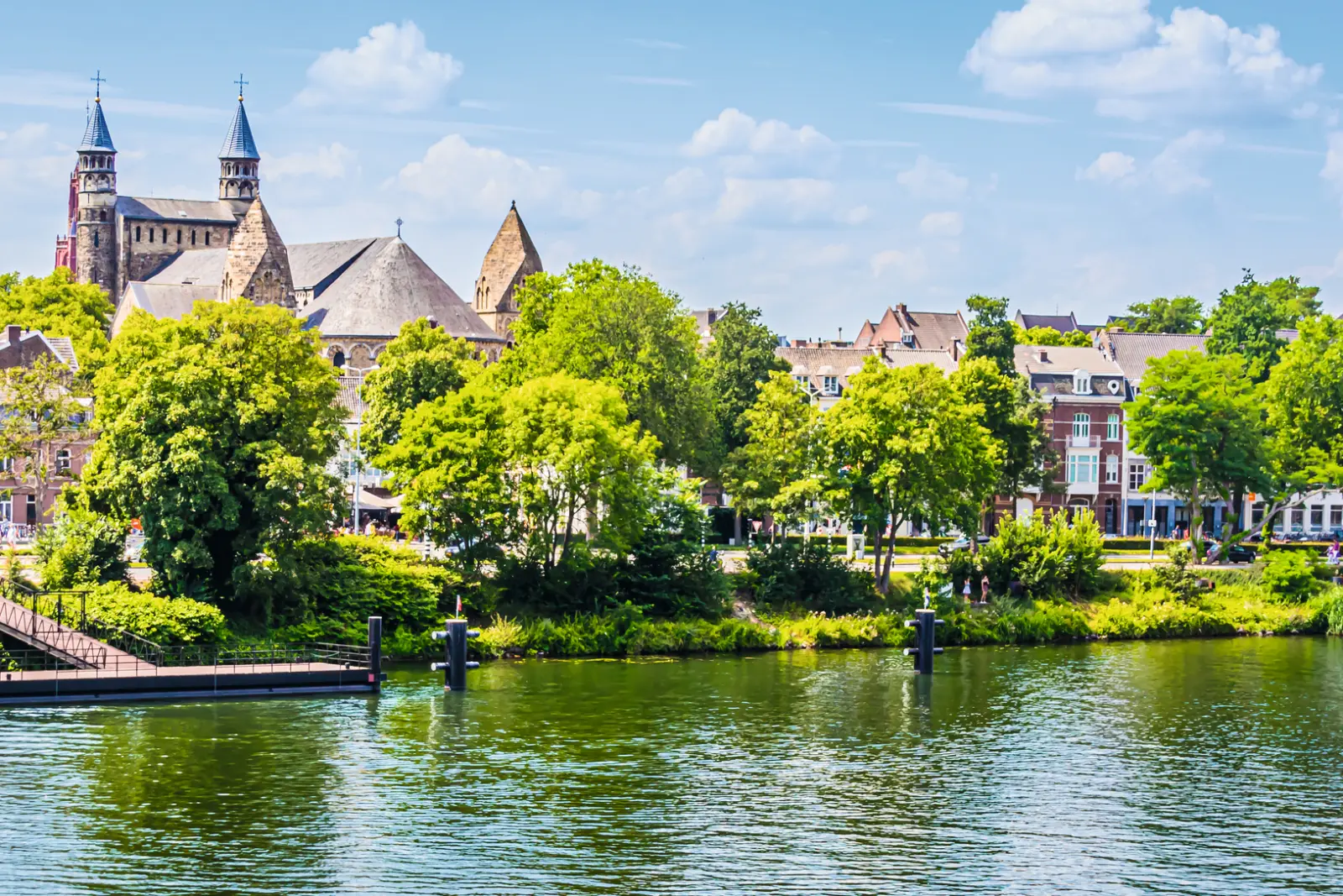 Veduta della città con chiesa e fiume sotto un cielo azzurro.