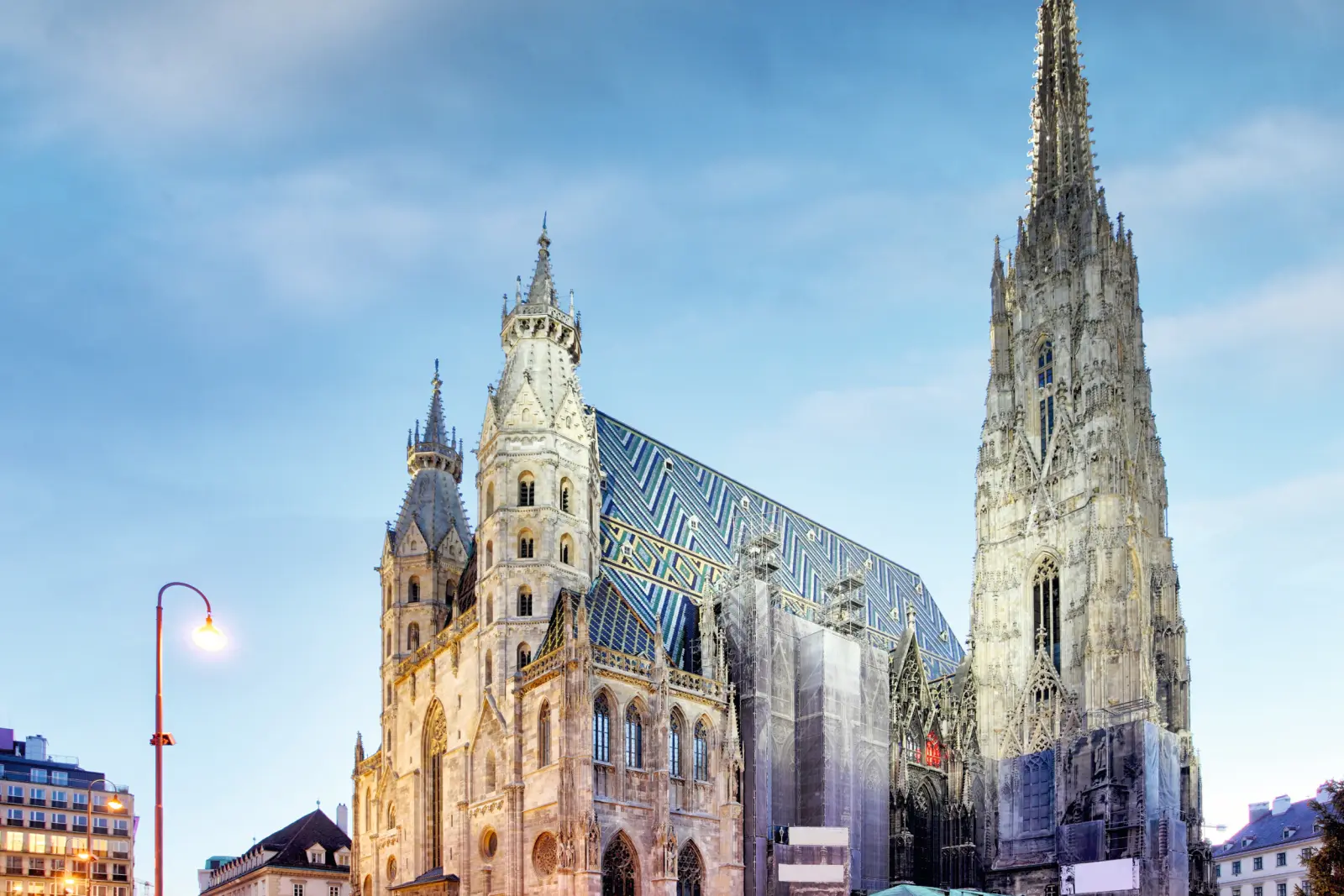 St. Stephen's Cathedral in Vienna at dusk with an illuminated square and a blue sky in the background.