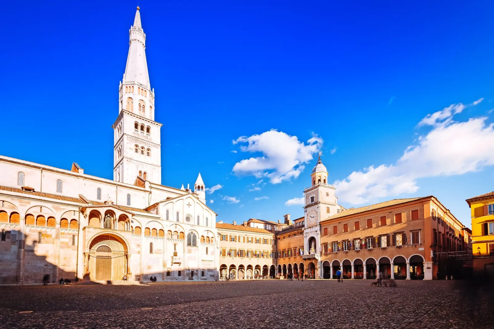 Piazza storica con cattedrale e campanile sotto un cielo azzurro.
