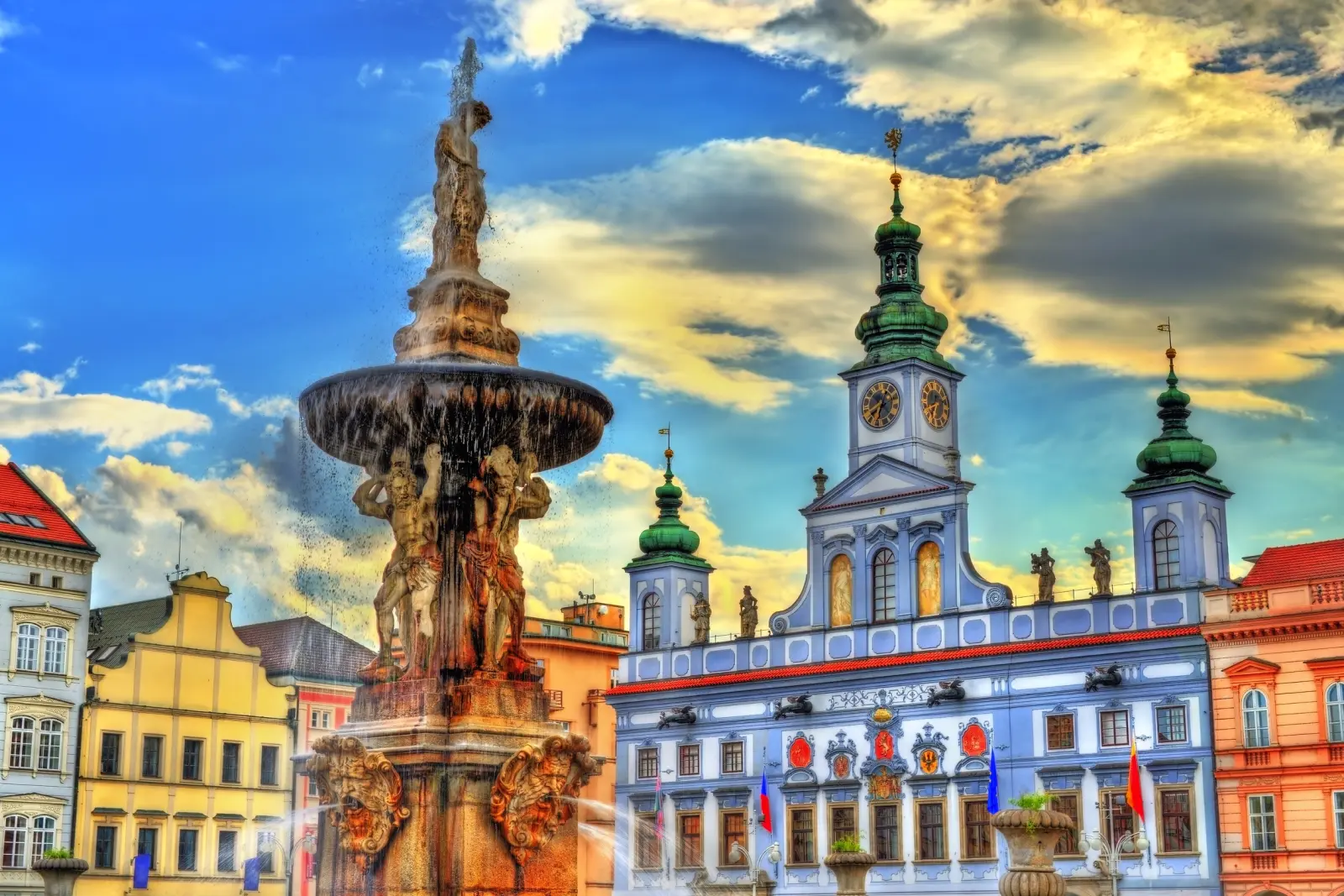 Historic fountain and colourful town hall under overcast skies