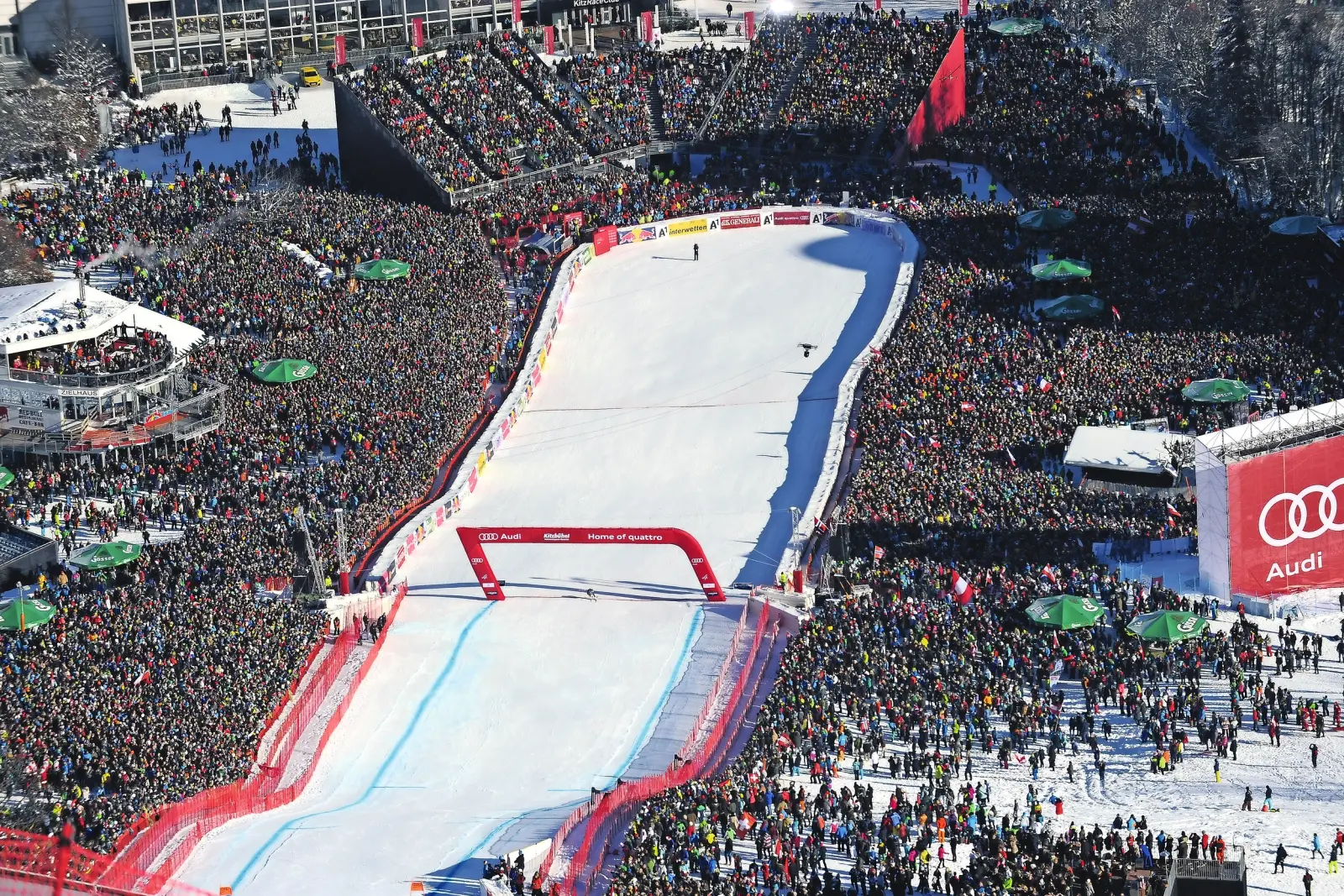 Large crowds watching a ski race on a snow-covered slope.