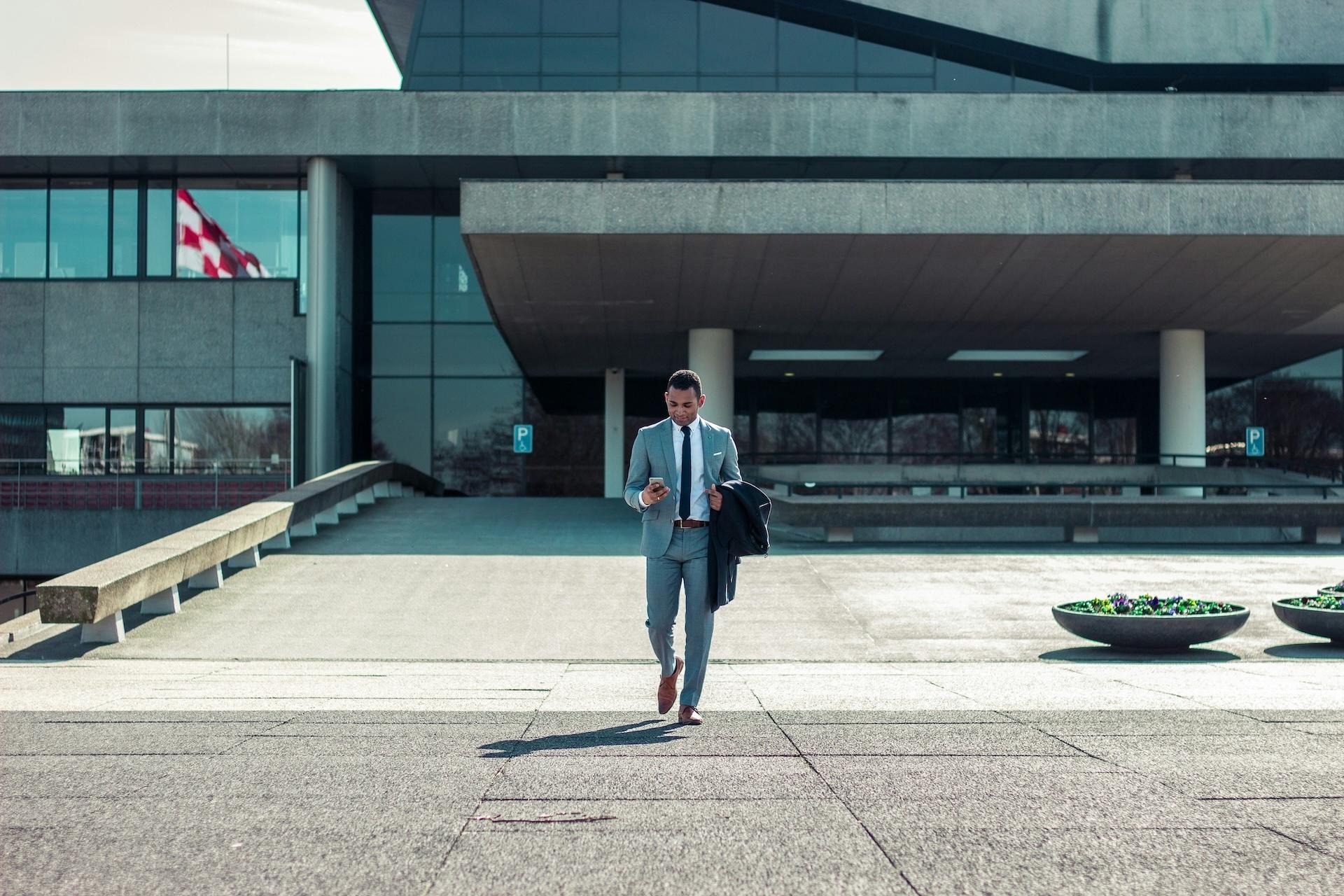 A businessman in a suit walking outside a modern office building.