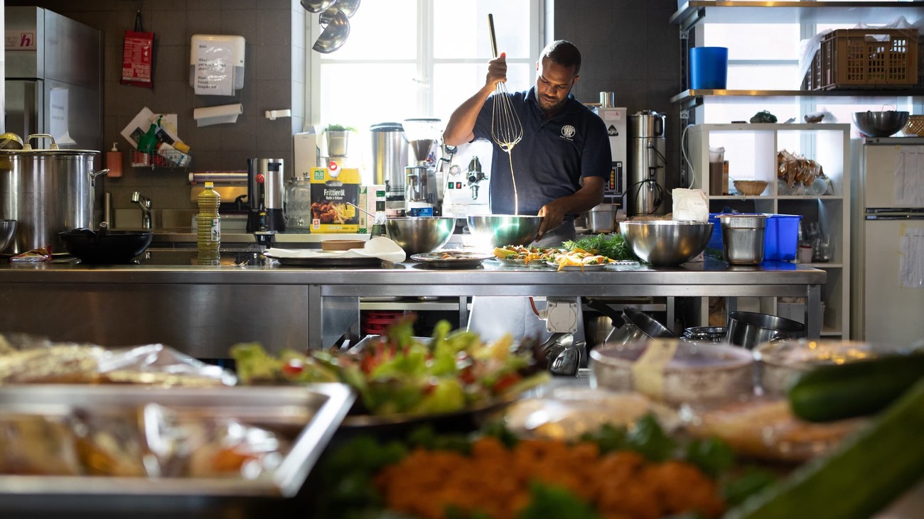 Homme en train de cuisiner. Mélange avec un fouet dans un saladier.